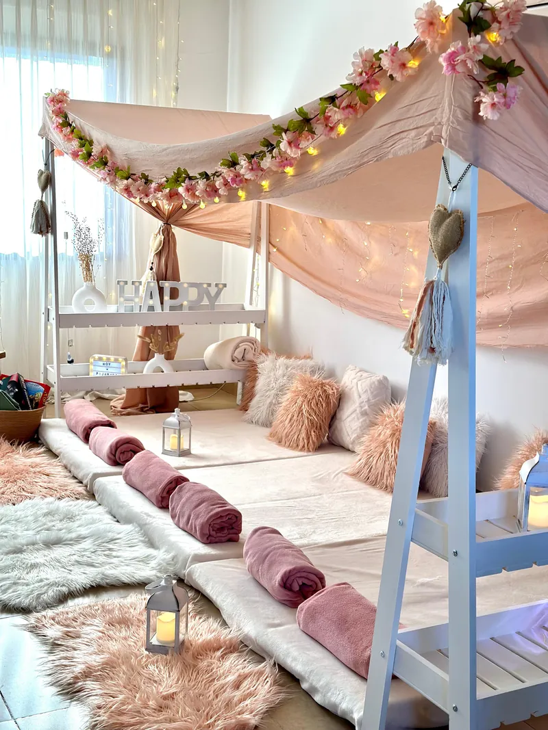 Glamping rosa con estructura compartida, flores, luces cálidas, colchonetas y mantitas listas para una pijamada